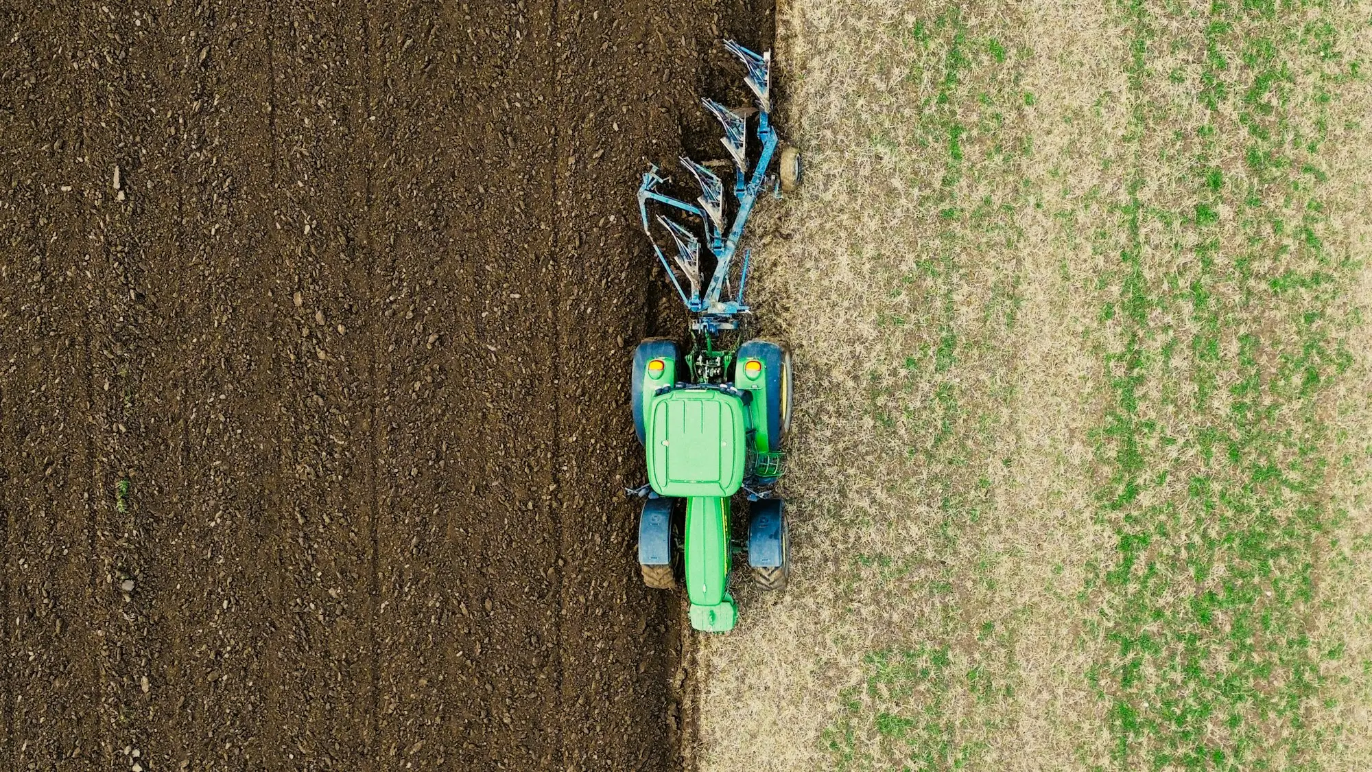 Aerial view of a tractor ploughing a paddock, the kind of owned-outright machinery a farm can refinance for cash