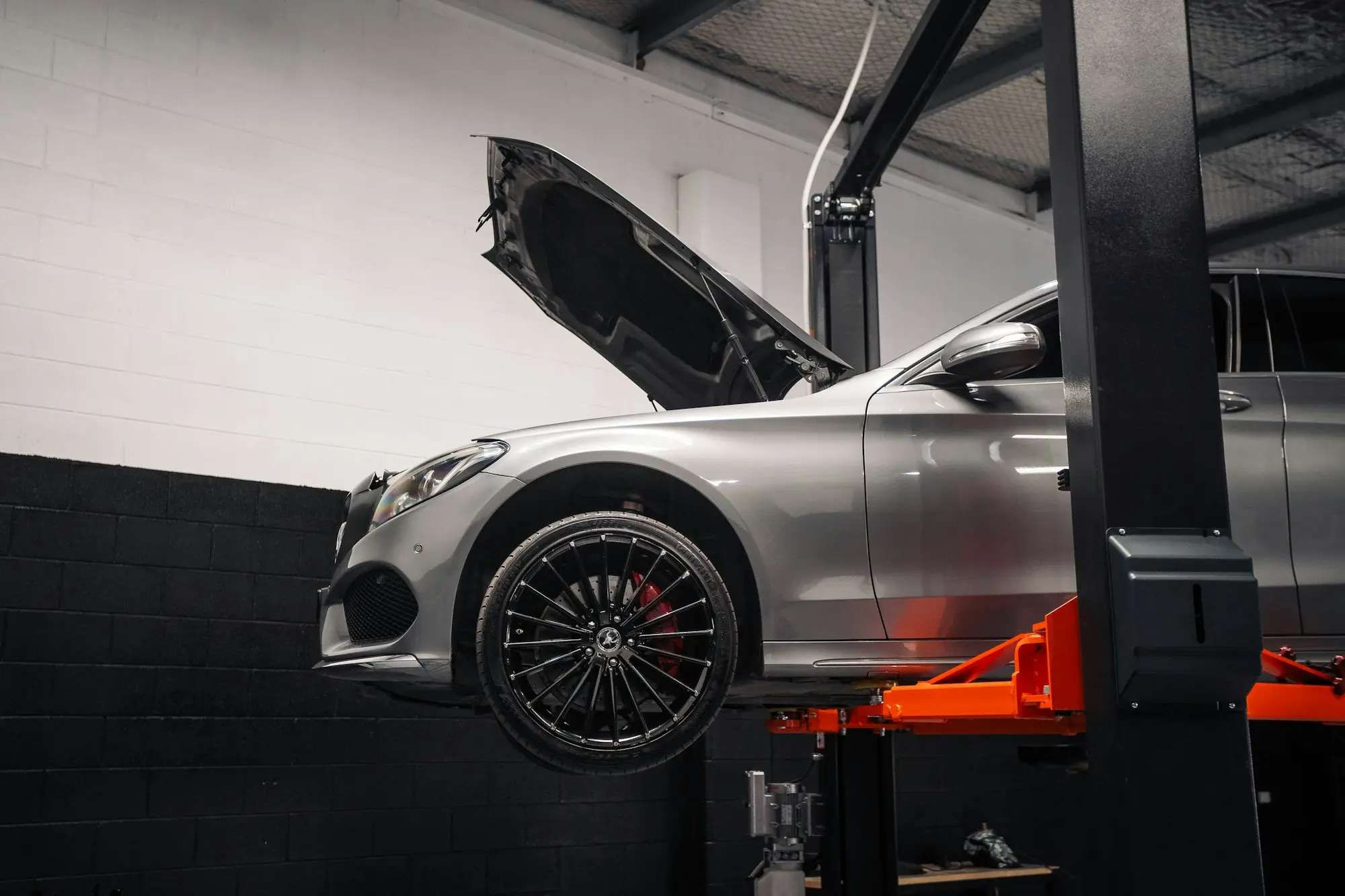 Silver car raised on an orange hoist in a tidy automotive workshop, a small business weighing up which fast loan suits its situation