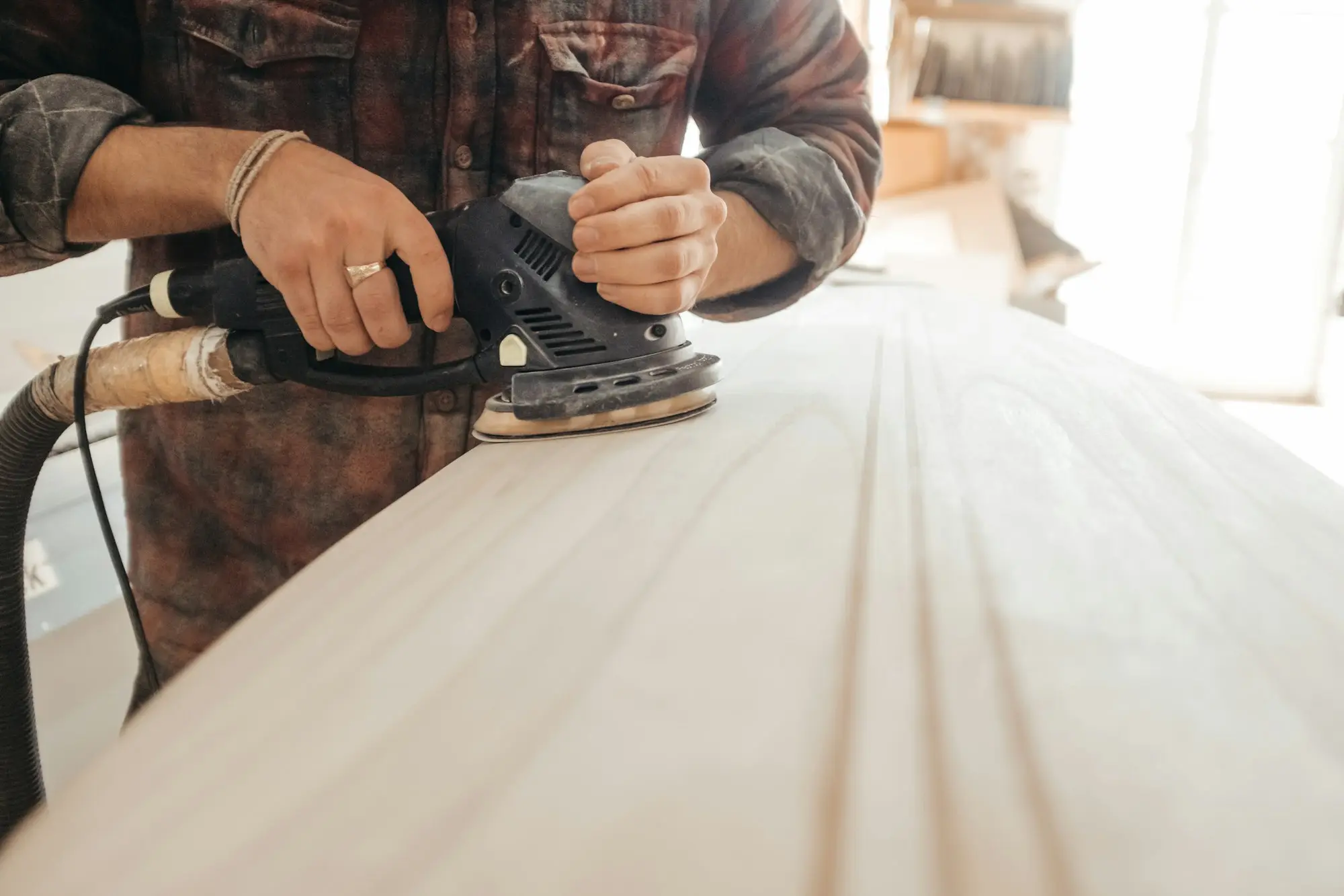 Joiner sanding a timber benchtop in a workshop, the kind of equipment a bank's all-assets GSA already covers