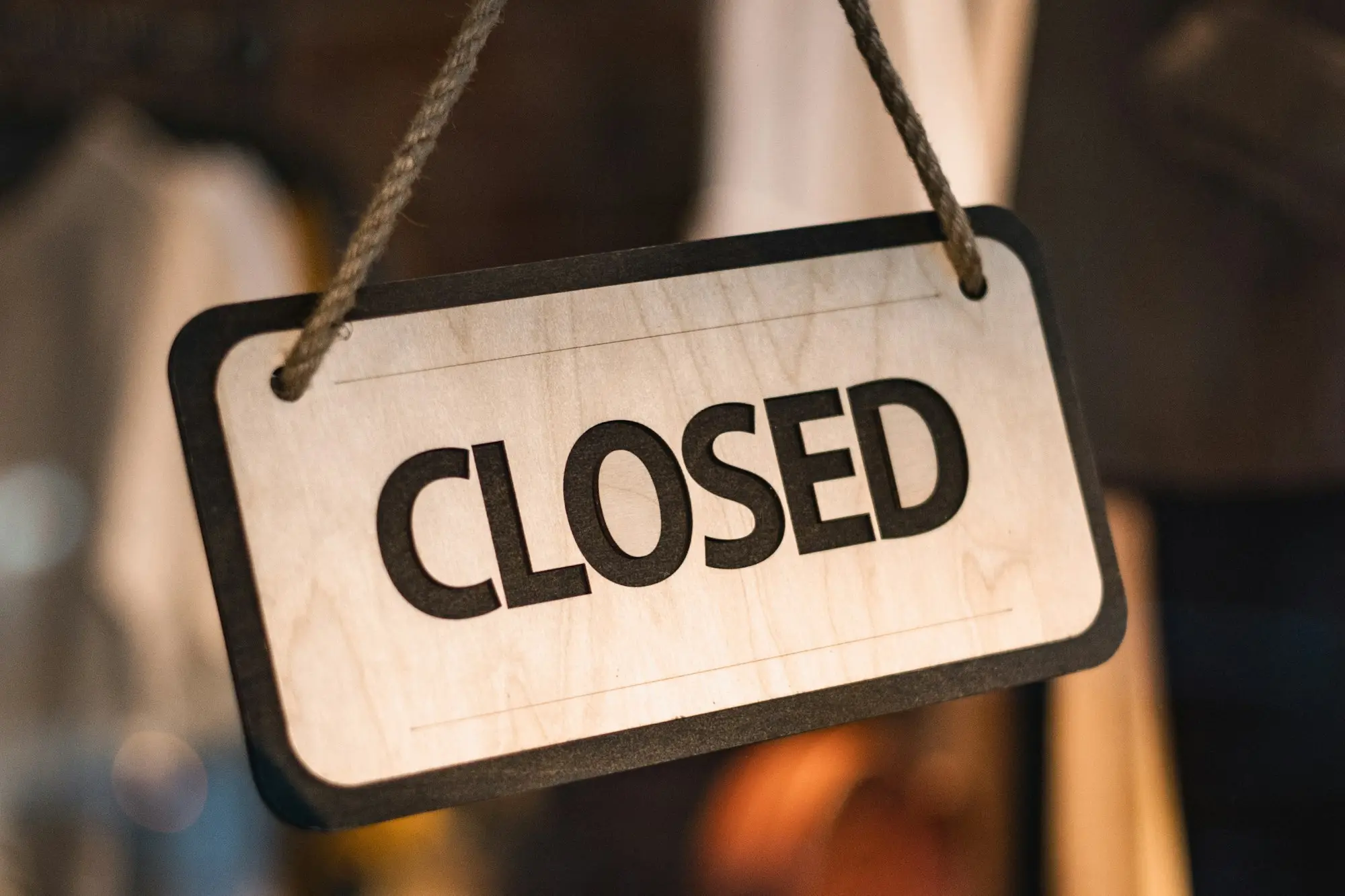 Wooden closed sign hanging in a shop door during the summer holiday shutdown